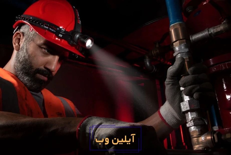 فردی با استفاده از چراغ قوه پیشانی در حال تعمیر در یک جای تعاریک